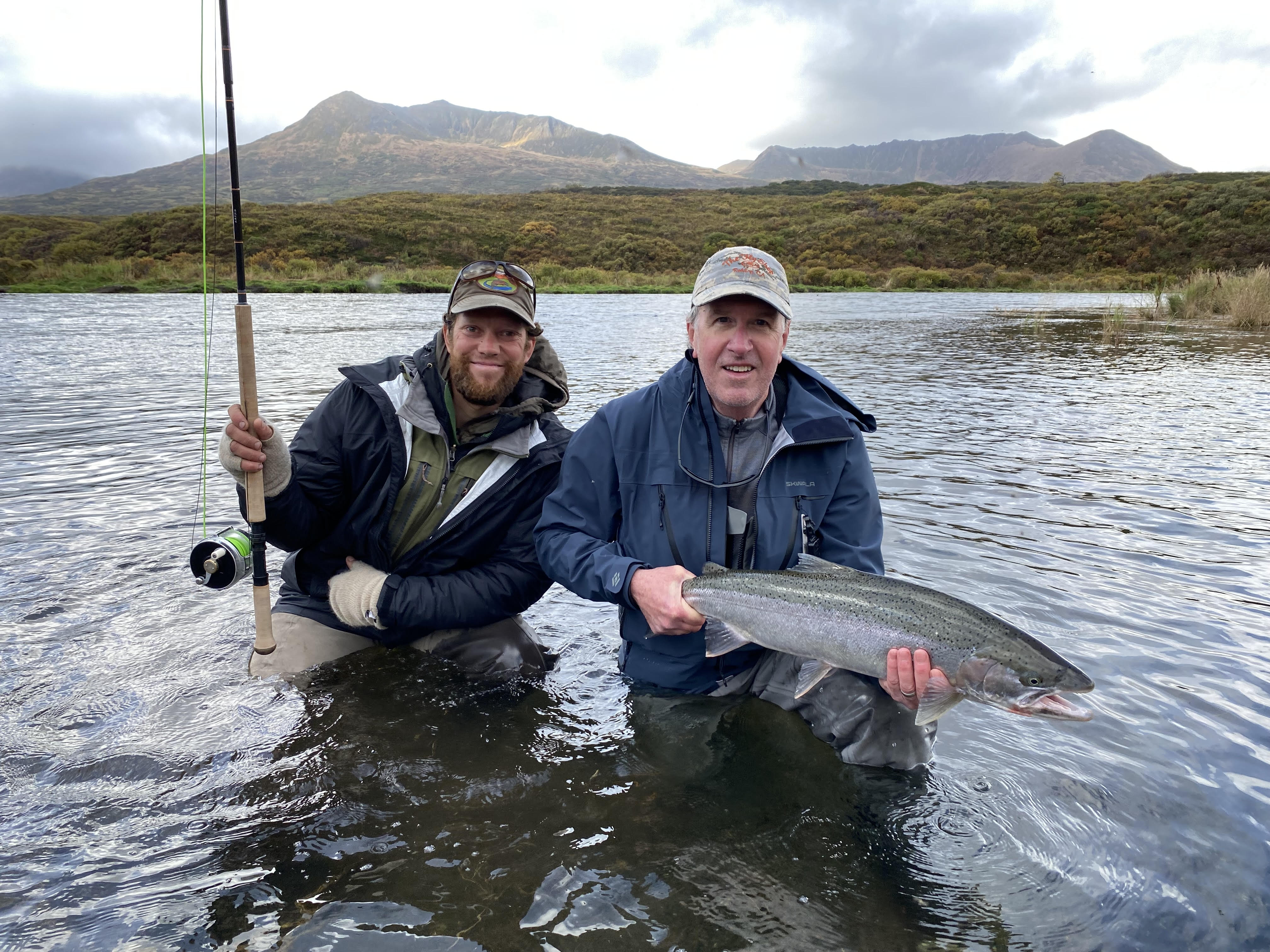 Two fishermen and a steelhead, in a river 